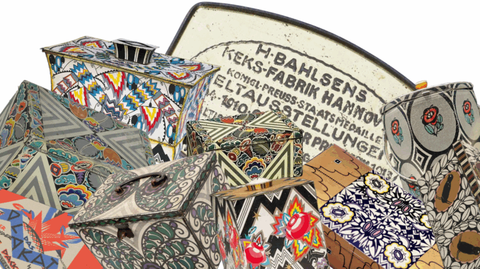 Eine farbenfrohe Auswahl an alten Art-Déco-Keksdosen mit geometrischen Mustern, Blumen, Zickzacklinien und kühnen Designs, die die Ästhetik der Epoche einfangen. Im Hintergrund ist auf einem Metalldeckel in schwarzer Schrift deutscher Text zu lesen.