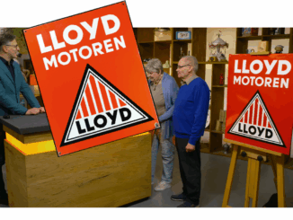 Drei Personen stehen in einem Studio mit Regalen und Antiquitäten, zwei halten ein großes rotes Lloyd-Emailschild mit der Aufschrift "LLOYD MOTOREN". Im Vordergrund ist eine vergrößerte Version geschnitten - eine klassische Bares für Rares-Szene mit einem restaurierten Vintage-Artikel.