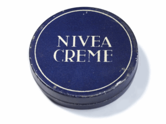 Eine runde, dunkelblaue Dose mit weißem Rand und dem Text "NIVEA CREME" in fetten weißen Großbuchstaben auf dem Deckel. Diese ikonische Dose stammt von 1925.