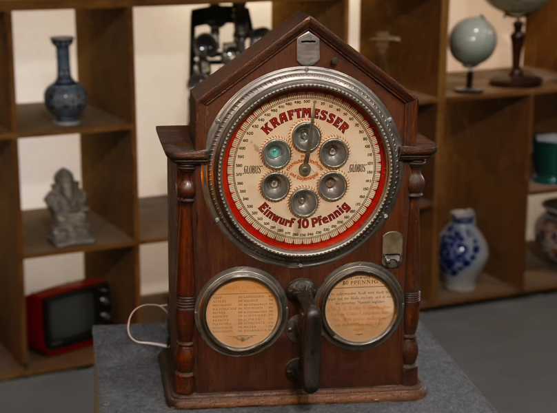 Bei dem abgebildeten Gerät handelt es sich um einen sogenannten Kraftmesser der Marke Globus, einen mechanischen Kraftprüfautomaten, wie er in den ersten Jahrzehnten des 20. Jahrhunderts vor allem auf Jahrmärkten, in Gaststätten und Vergnügungslokalen anzutreffen war. 