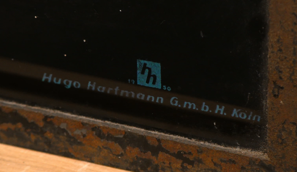 Das Schild wurde bei Hugo Hartmann in Köln produziert. Am Monogramm erkennt man das wahrscheinliche Produktionsdatum, das Jahr 1950 